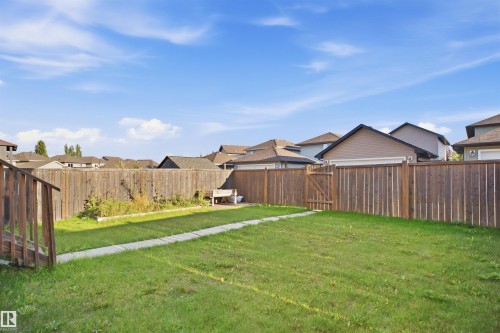 Expansive backyard featuring a lush lawn, privacy fencing, a concrete paver pathway, and a wooden gate - 1523 36 Avenue Nw, Edmonton, AB 