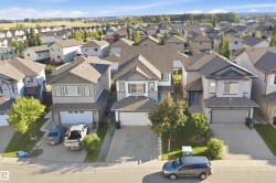 Two-story residence featuring an attached garage, paved driveway, and mature front yard landscaping - 