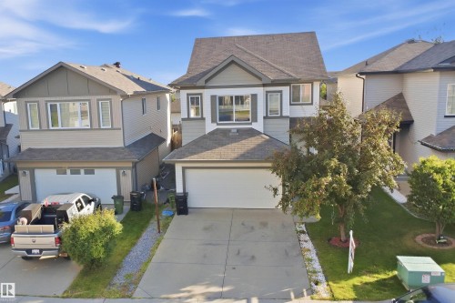 Two-story residence featuring a two-car attached garage, mature front yard tree, and an asphalt shingle roof - 1523 36 Avenue Nw, Edmonton, AB 