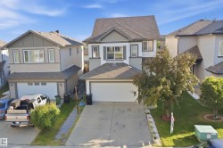 Two-story residence featuring a two-car attached garage, mature front yard tree, and an asphalt shingle roof - 