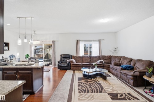 Hardwood-style flooring throughout, kitchen island with granite-style countertop, built-in cabinetry with stainless steel sink, pendant lighting fixtures, and sliding glass door - 1523 36 Avenue Nw, Edmonton, AB 