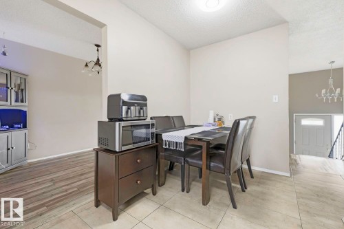 Archway entry, wood-finish flooring, ceramic tile flooring, built-in cabinetry, and a contemporary chandelier - 3216 138 Avenue Nw, Edmonton, AB 