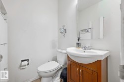 White ceramic toilet, wood-finish vanity with integrated sink, chrome faucet, and wall-mounted mirror - 