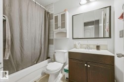 White subway tile surround, white bathtub, corner vanity with dark wood-finish cabinetry, white countertop, and wall-mounted medicine cabinet - 