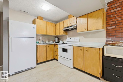 Kitchen featuring light wood-finish cabinetry, white countertops, a white top-freezer refrigerator, a white electric range, and a stainless steel range hood - 3216 138 Avenue Nw, Edmonton, AB 