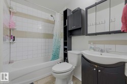 Bathroom featuring a bathtub with tile surround, toilet, vanity with integrated sink, and wall-mounted medicine cabinet - 