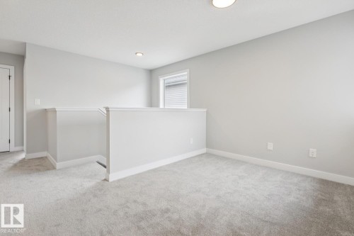 Carpeted landing area featuring a contemporary railing, recessed lighting, and a window with blinds - 72 Maple Crescent, Gibbons, AB 