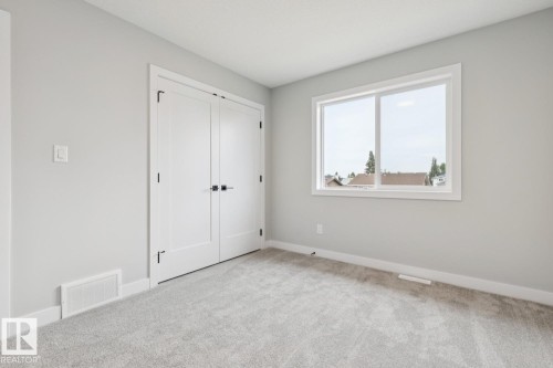 Soft gray wall finish, light gray carpet flooring, white trim, and a white framed window - 72 Maple Crescent, Gibbons, AB 