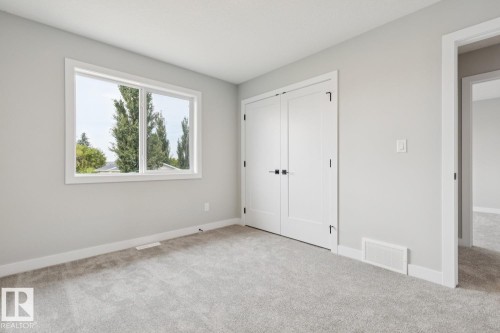 Broadloom carpeting, light grey wall paint, white trim, and a window with white casing - 72 Maple Crescent, Gibbons, AB 
