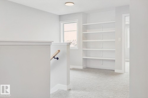 Built-in shelving, natural wood handrail, recessed ceiling light, and light-toned carpeting - 72 Maple Crescent, Gibbons, AB 