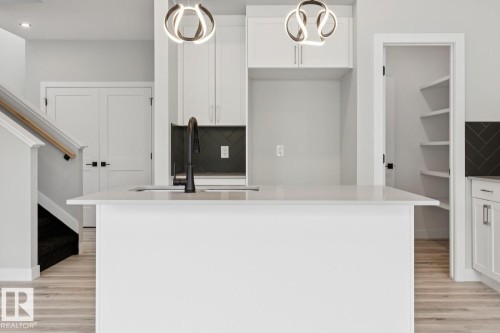 Kitchen island featuring an undermount sink and matte black faucet - 36 Maple Crescent, Gibbons, AB 