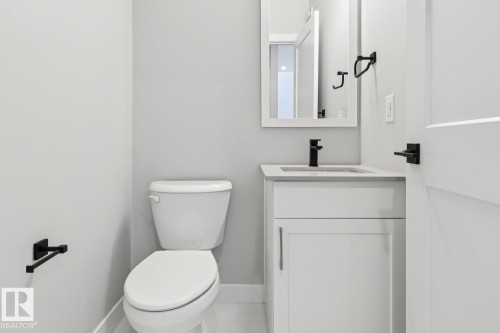 White vanity with a rectangular sink, black faucet, and coordinating mirror - 36 Maple Crescent, Gibbons, AB 