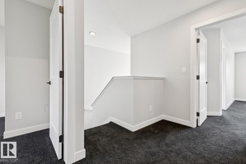 Upper floor landing featuring dark gray carpeting and white interior doors with dark hardware - 36 Maple Crescent, Gibbons, AB 