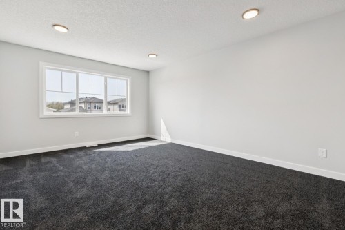 Recessed lighting, large window with white trim, dark gray carpeting, and light-colored walls - 36 Maple Crescent, Gibbons, AB 