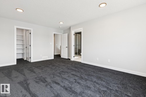 Spacious room with dark gray carpeting, recessed ceiling lighting, and multiple white panel doors - 36 Maple Crescent, Gibbons, AB 