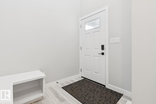 White paneled entry door with an upper window insert, smart lock, and matte black hardware - 36 Maple Crescent, Gibbons, AB 