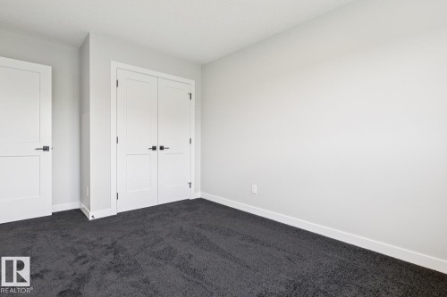 Bright bedroom with clean white walls, dark carpet flooring, and abundant natural light from overhead fixtures - 36 Maple Crescent, Gibbons, AB 