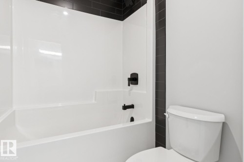 White bathtub with matte black fixtures and a tiled surround - 36 Maple Crescent, Gibbons, AB 