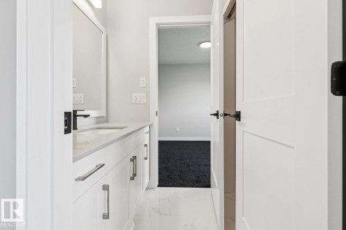 White vanity with integrated sink, matte black faucet, and mirrored medicine cabinet - 36 Maple Crescent, Gibbons, AB 