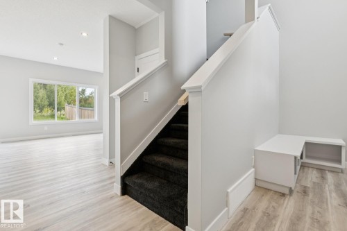 Staircase with dark carpeted treads, wood-finish flooring, recessed lighting, and a built-in storage bench - 36 Maple Crescent, Gibbons, AB 