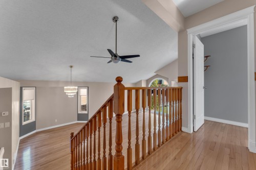 Hardwood flooring throughout, a wood baluster railing, an overhead ceiling fan, a tiered chandelier, and an arched window - 9722 157 Street Nw, Edmonton, AB 
