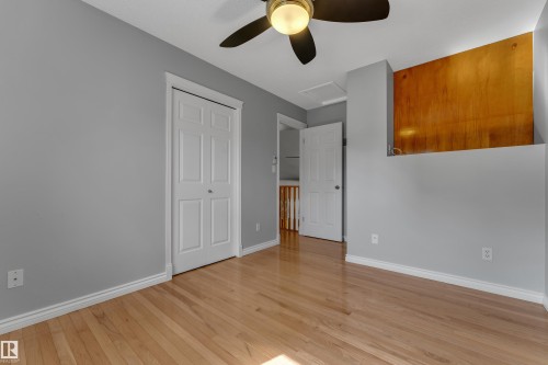 Hardwood flooring, neutral gray wall tones, ceiling fan, and white bi-fold closet doors - 9722 157 Street Nw, Edmonton, AB 