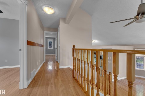 Wood-finish flooring throughout, light neutral wall paint, and a wood railing with turned spindles - 9722 157 Street Nw, Edmonton, AB 