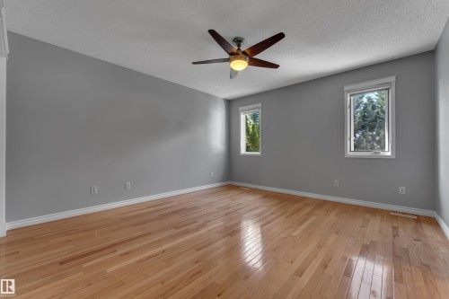 Hardwood flooring, painted walls, white trim, two windows, and a ceiling fan with integrated lighting - 9722 157 Street Nw, Edmonton, AB 
