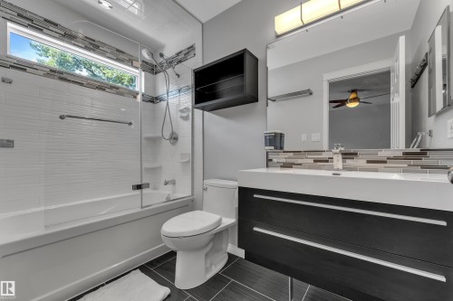 Built-in vanity with integrated sink, dark wood-finish cabinetry, and a full-width mirror - 9722 157 Street Nw, Edmonton, AB 