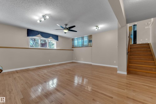 Spacious room featuring wood-finish flooring, multiple windows, a ceiling fan, and track lighting - 9722 157 Street Nw, Edmonton, AB 