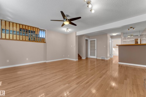 Light wood-finish flooring, ceiling fan with integrated lighting, track lighting, and a wood-finish railing - 9722 157 Street Nw, Edmonton, AB 