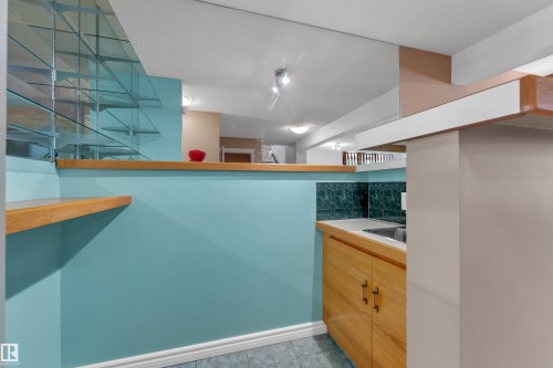 Built-in wet bar featuring wood-finish cabinetry, a stainless steel sink, tiled backsplash, and glass shelving - 9722 157 Street Nw, Edmonton, AB 