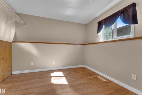 Wood-finish flooring with white trim, a single window, and a built-in wire shelving unit - 9722 157 Street Nw, Edmonton, AB 