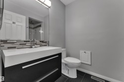 Modern vanity with integrated sink, sleek dark cabinetry, contemporary faucet, mosaic tile backsplash, and large wall-mounted mirror - 