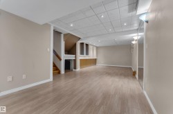 Spacious room featuring wood-finish flooring, recessed lighting, built-in cabinetry, and a carpeted staircase with wood railing - 