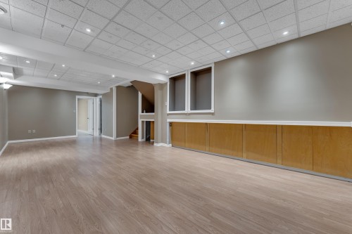 Expansive open-concept room featuring wood-finish flooring, recessed ceiling lights, and integrated wall paneling - 9722 157 Street Nw, Edmonton, AB 