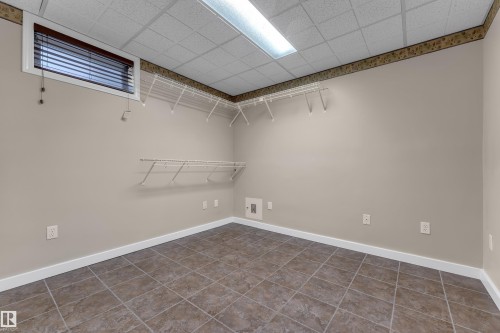 Ceramic tile flooring, drop ceiling with fluorescent lighting, window with horizontal blinds, built-in wire shelving, and neutral wall tones - 9722 157 Street Nw, Edmonton, AB 
