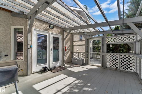 Covered deck featuring a corrugated translucent roof, wood-finish decking, and lattice privacy screens - 9722 157 Street Nw, Edmonton, AB 