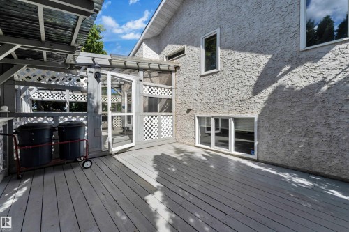 Expansive wood-finish deck with a latticework privacy wall, covered pergola, and multiple large windows - 9722 157 Street Nw, Edmonton, AB 