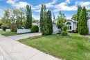 Exterior featuring a curved architectural window, attached garage, concrete driveway, and mature landscaping - 9722 157 Street Nw, Edmonton, AB 