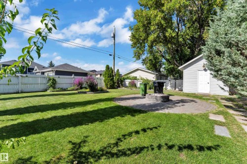 Expansive lawn area, white privacy fencing, paved patio, stone-finish fire pit, and a detached shed with siding - 9722 157 Street Nw, Edmonton, AB 