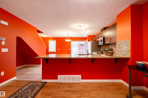 Kitchen with wood-finish flooring, stainless steel appliances, and a mosaic tile backsplash - #31 460 Hemingway Rd Nw, Edmonton, AB 