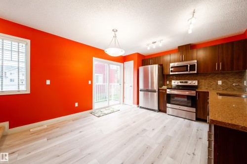 Light wood-finish flooring with a matching kitchen island featuring a stone countertop - #31 460 Hemingway Rd Nw, Edmonton, AB 