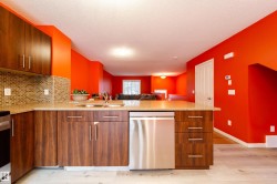 Kitchen featuring wood-finish cabinetry, stainless steel dishwasher, and mosaic tile backsplash - 