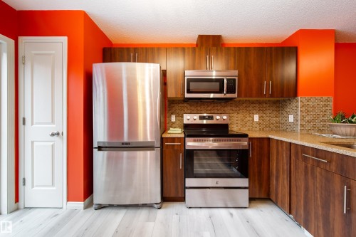 Stainless steel appliances, wood-finish cabinetry, mosaic tile backsplash, composite countertops, and wood-finish flooring - #31 460 Hemingway Rd Nw, Edmonton, AB 