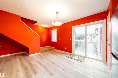 Light wood-finish flooring throughout, bright red walls, white trim, and a white ceiling - #31 460 Hemingway Rd Nw, Edmonton, AB 