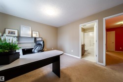 Carpeted flooring throughout, neutral wall paint, and a built-in desk with overhead shelving - 