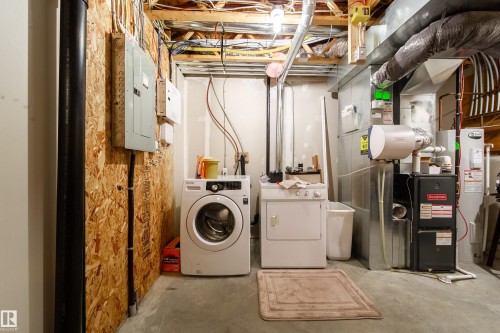 Utility area featuring a washer and dryer, exposed ceiling joists, and concrete flooring - #31 460 Hemingway Rd Nw, Edmonton, AB 