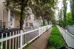 Concrete walkway with a decorative white fence, flanked by vibrant green landscaping - 