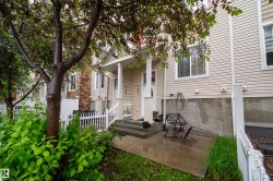 Private patio space with concrete flooring, white picket fence, and mature tree - 